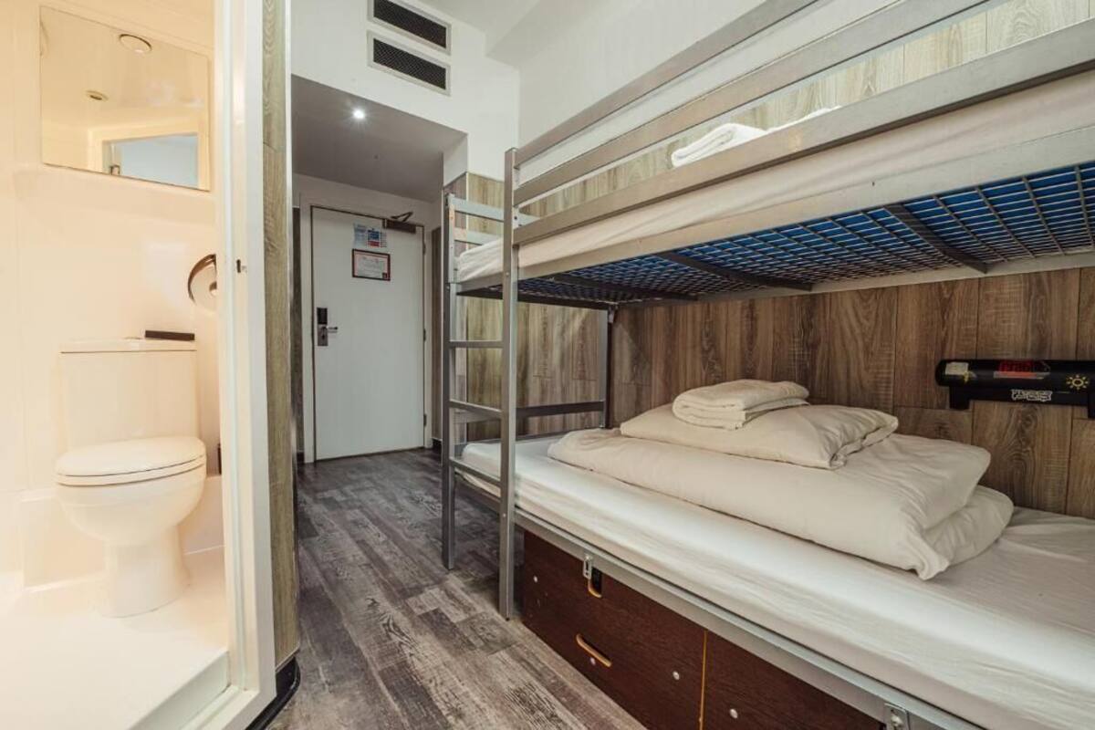A bunk bed room with a wooden wall, a white toilet, and a small window.