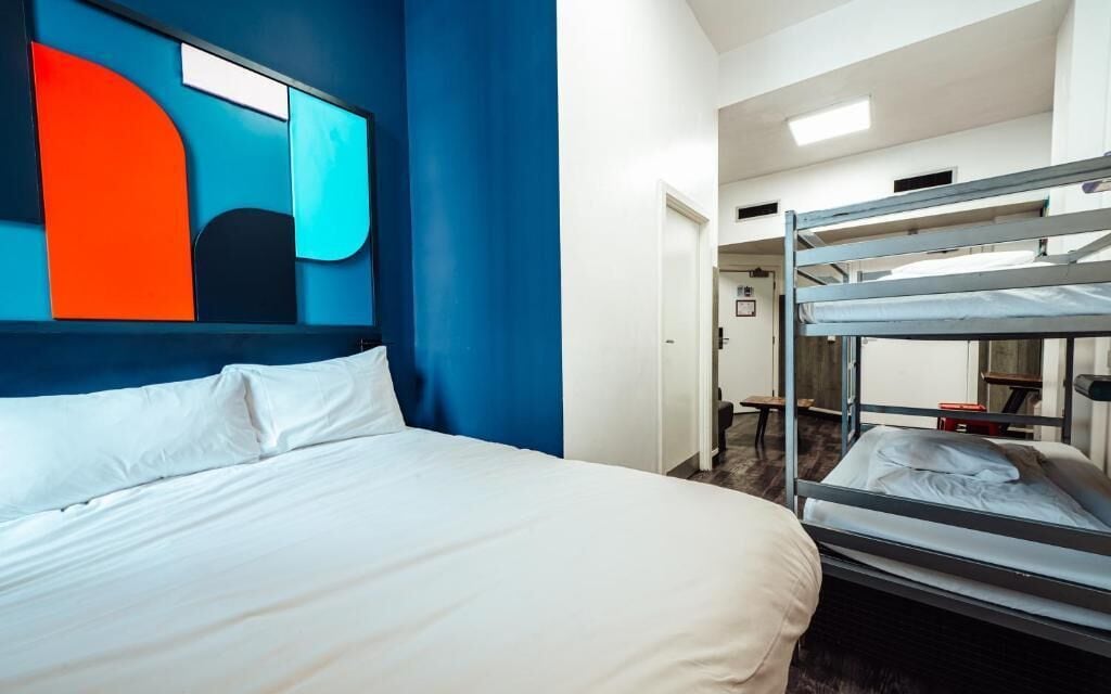 Ein Hotelzimmer mit Etagenbett, einem großen Bett und einem modernen Wandbild im abstrakten Stil.