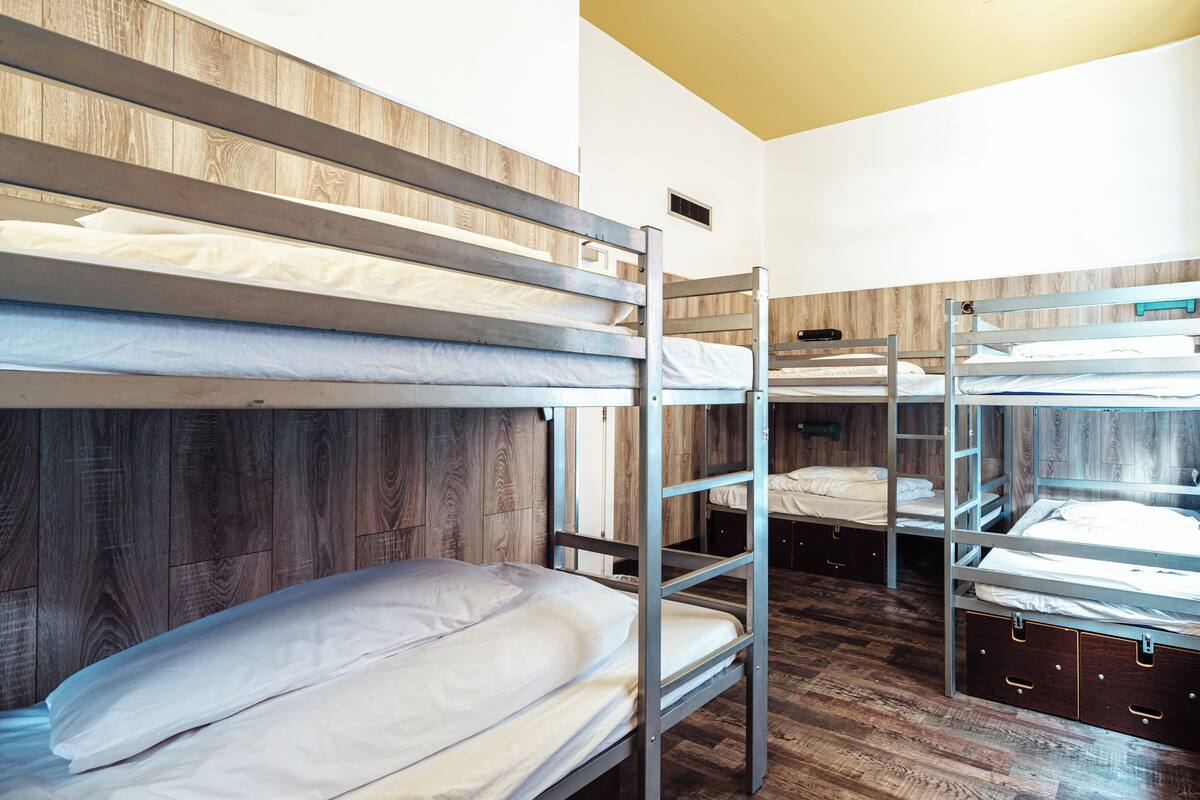 A bunk bed room with wooden walls and a yellow ceiling.