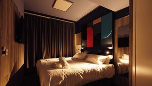 A hotel room with a large bed, a flat-screen TV mounted on the wall, and a wooden wardrobe.