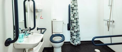 A bathroom with a white sink, a toilet, a shower with a glass door, and a mirror with black frames.