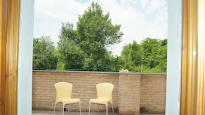 Eine Terrasse im Freien mit zwei gelben Stühlen und einer Ziegelwand.
