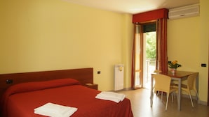 Ein Hotelzimmer mit einem großen Bett, einem kleinen Tisch mit Stühlen und einem Fenster mit Vorhängen.
