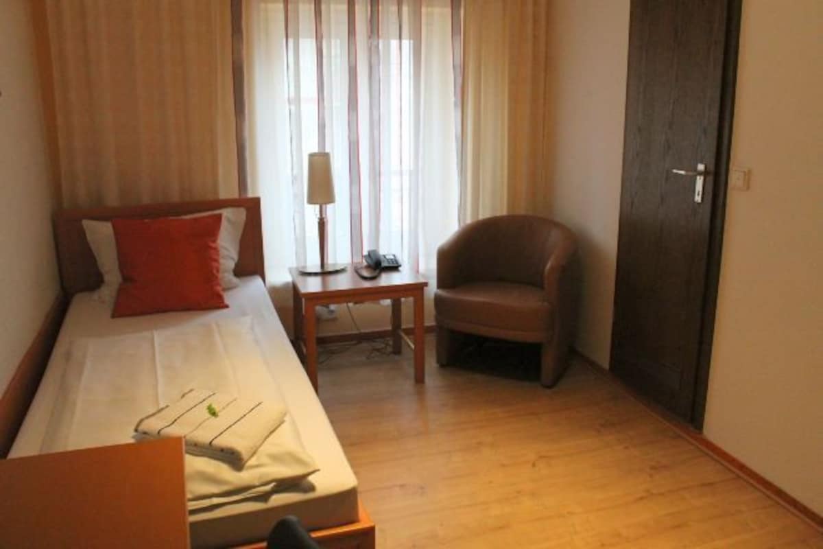 Une chambre d’hôtel avec un lit, une chaise, une table et une armoire.