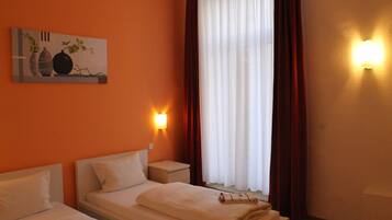 Ein Hotelzimmer mit zwei Betten, einem Bild an der Wand und einem Fenster mit Vorhängen.