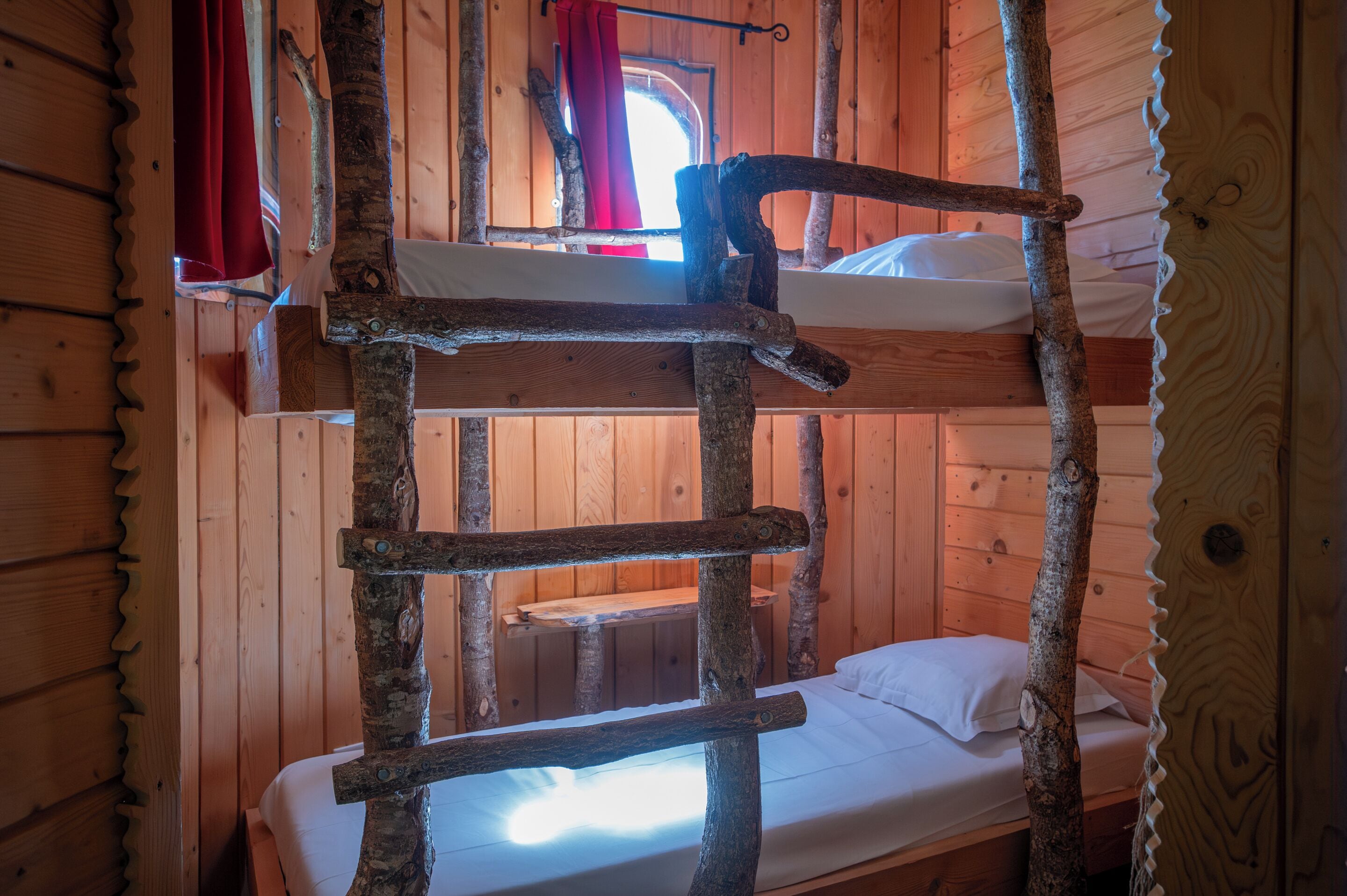 Una cama litera con escalera en una habitación tipo cabaña de madera.