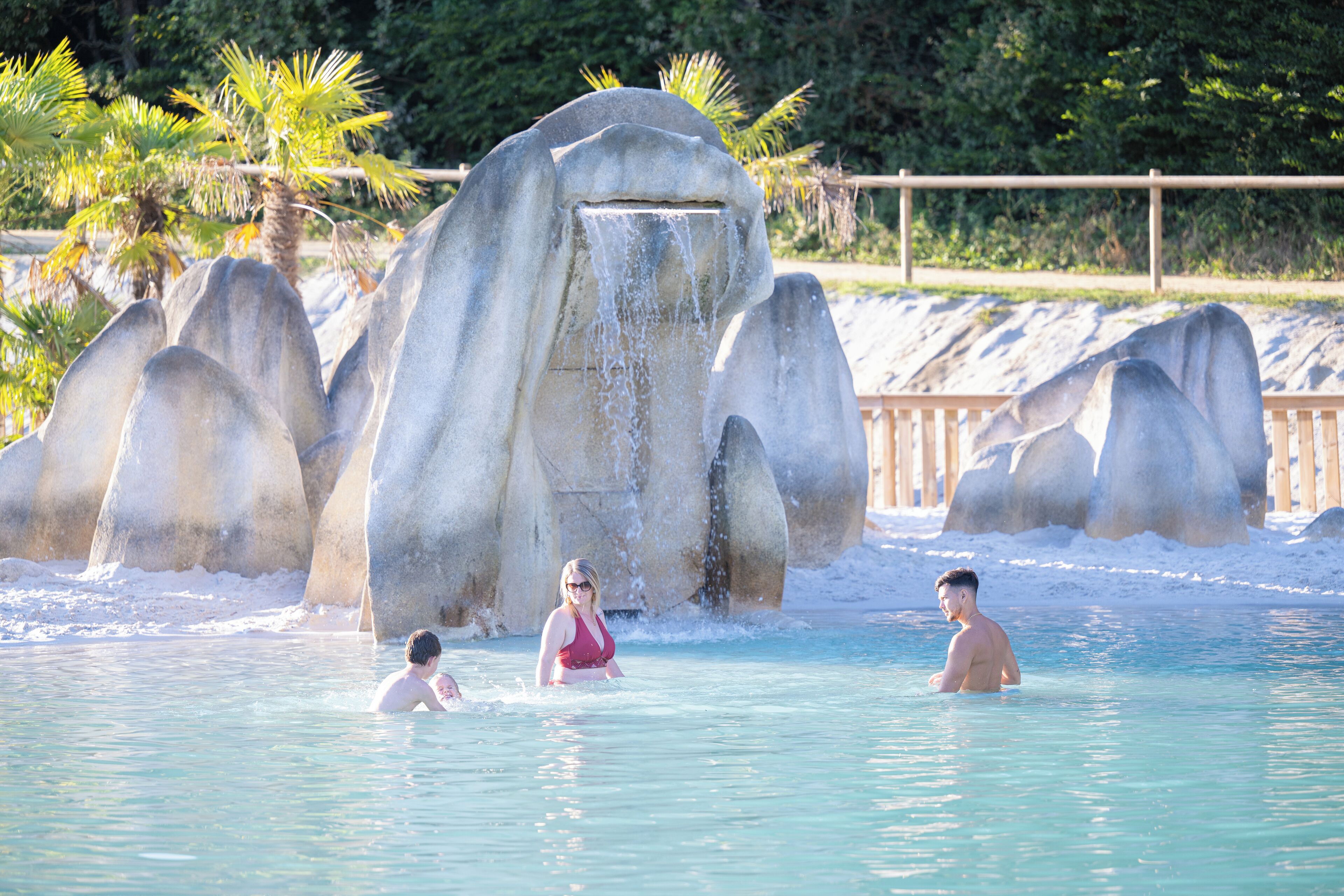 Une piscine bordée de grandes formations rocheuses, avec des palmiers en arrière-plan.