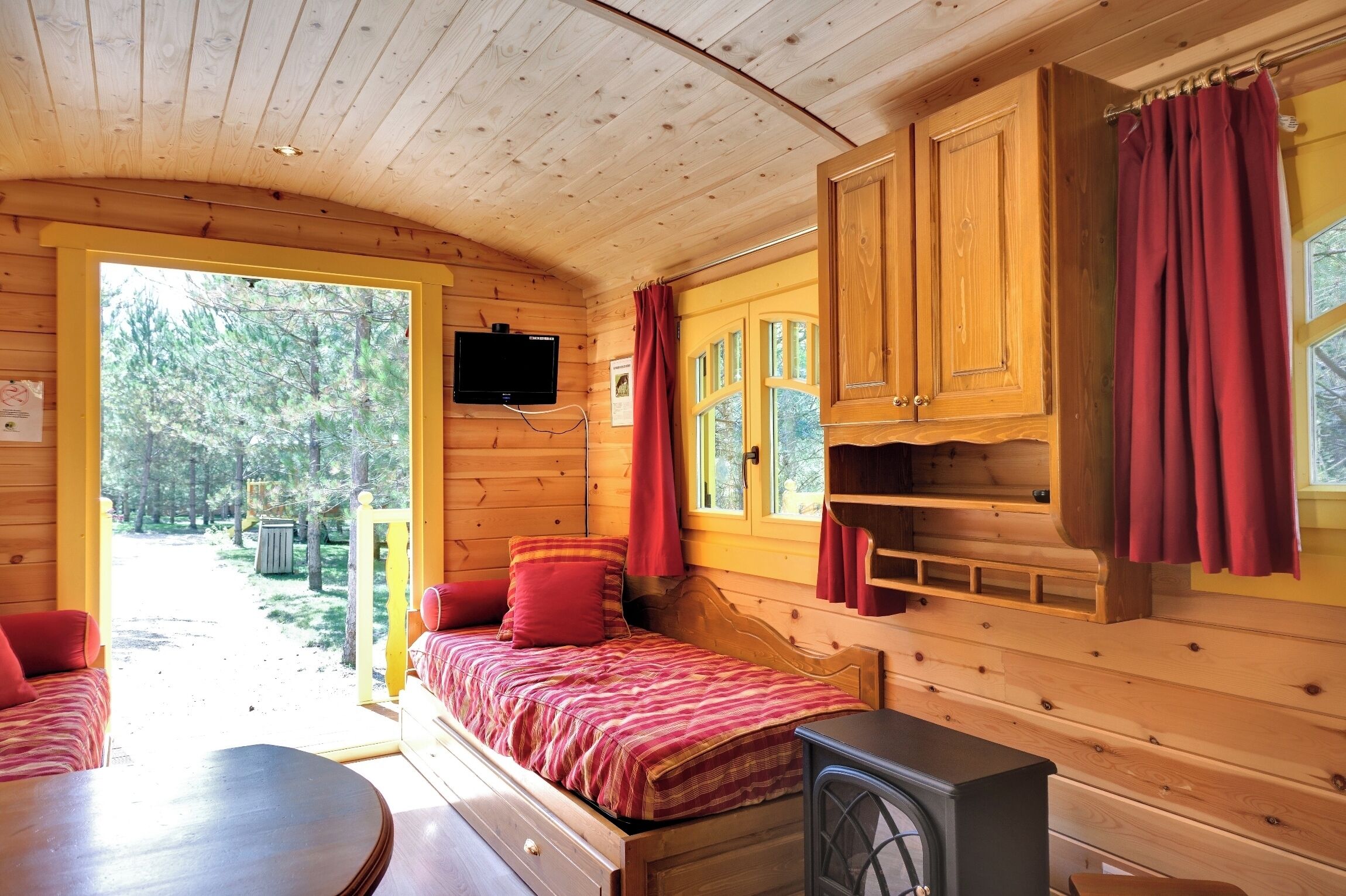 Une cabane confortable avec un lit, un téléviseur et des armoires en bois.