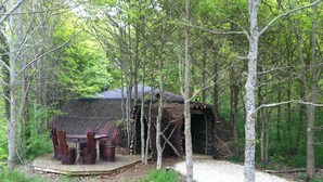 A rustic cabin with a thatched roof, surrounded by trees. - Domaine de Dienné (Dienne)
