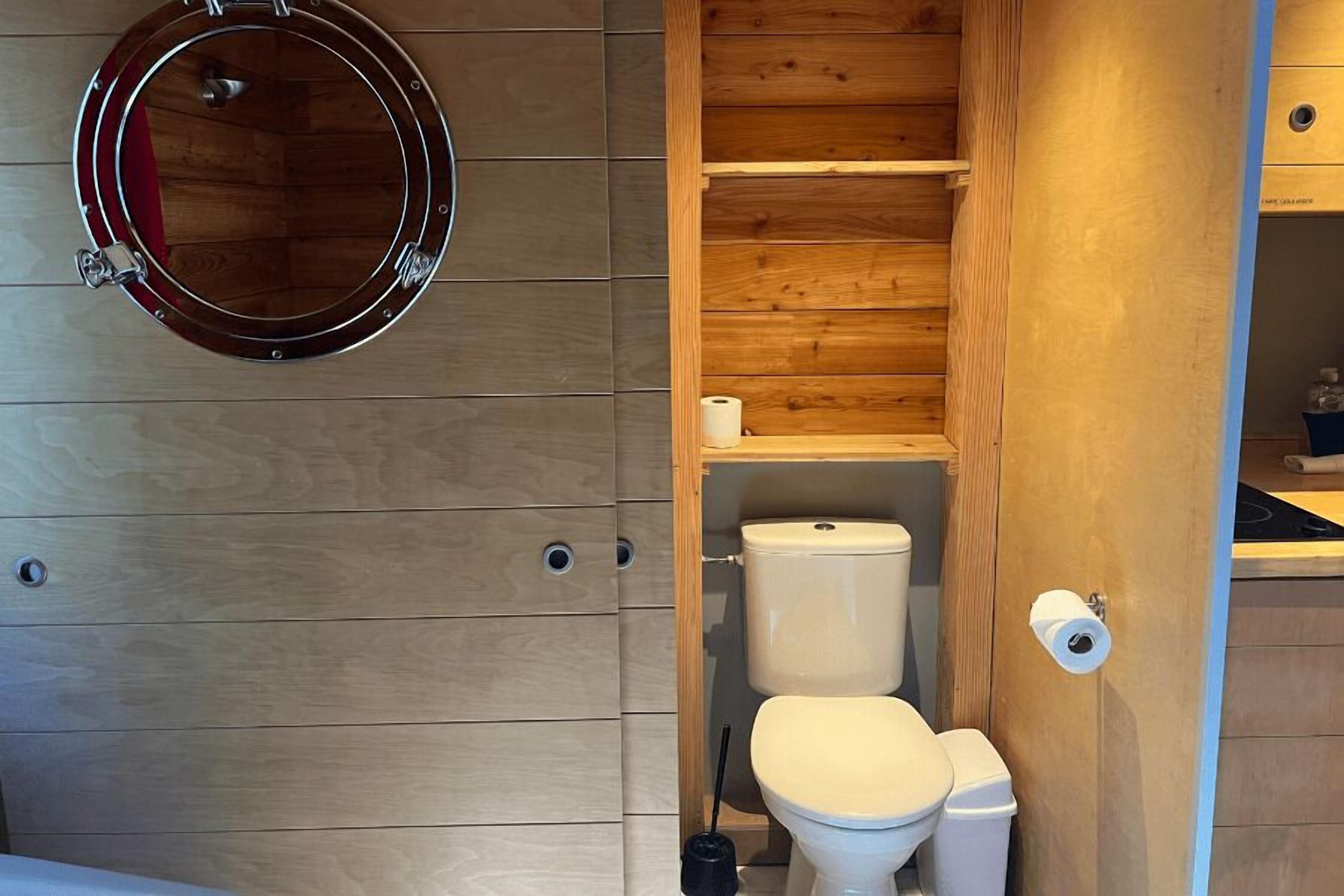 Une petite salle de bain avec un meuble-lavabo en bois, des toilettes et un miroir.