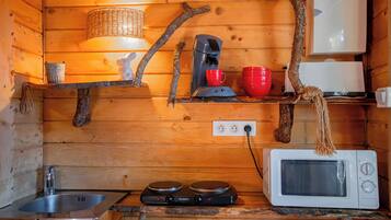 Eine kleine Küche mit Spüle, Kaffeemaschine, Mikrowelle und Toaster.