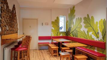A restaurant with wooden furniture, red cushioned benches, and a wall mural of leaves.
