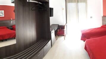 Quarto de hotel com duas camas, um espelho, uma escrivaninha e uma cadeira.