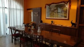 A dining area with a long wooden table, chairs, and a decorative mirror on the wall.
