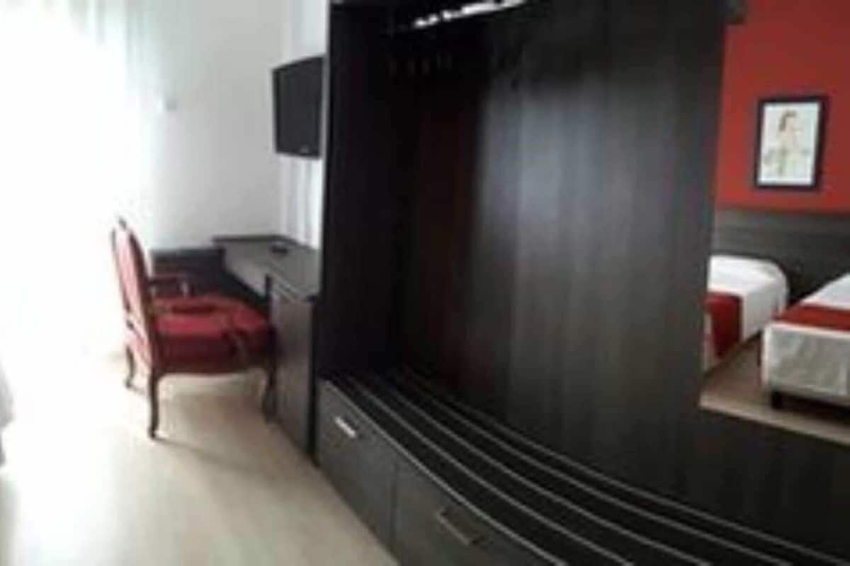 A hotel room with two beds, a TV, a desk, and a chair.