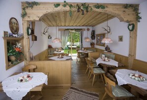 A rustic dining area with wooden benches and tables, a wooden archway, and hanging lanterns. - Chalet Garni Hotel Zimmermann (Reith bei Kitzbuehel)