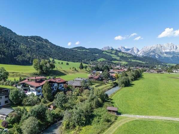 A rural village with houses, a river, and mountains in the background.