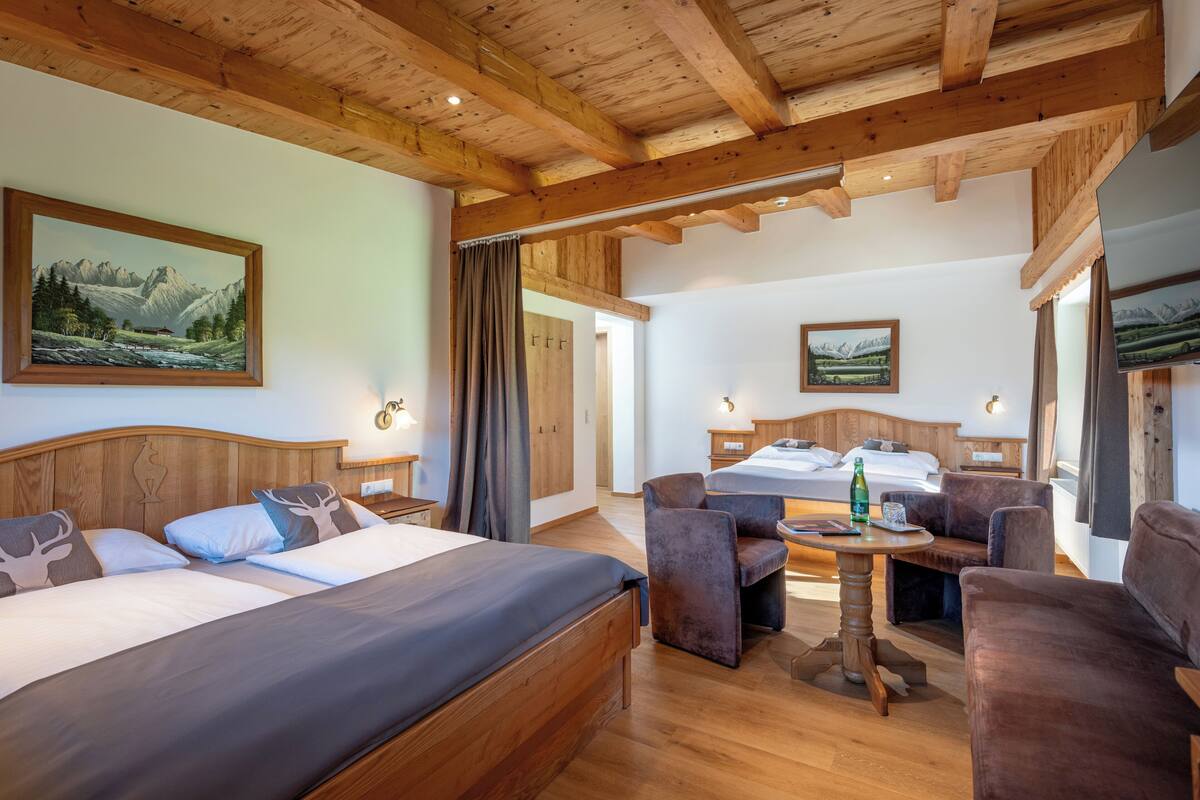 Ein Hotelzimmer mit Holzboden, zwei Betten, einer Sitzecke mit Tisch und Stühlen sowie einem Fernseher.
