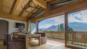 Interior de madera con comedor, ventanas amplias y vistas a la montaña.
