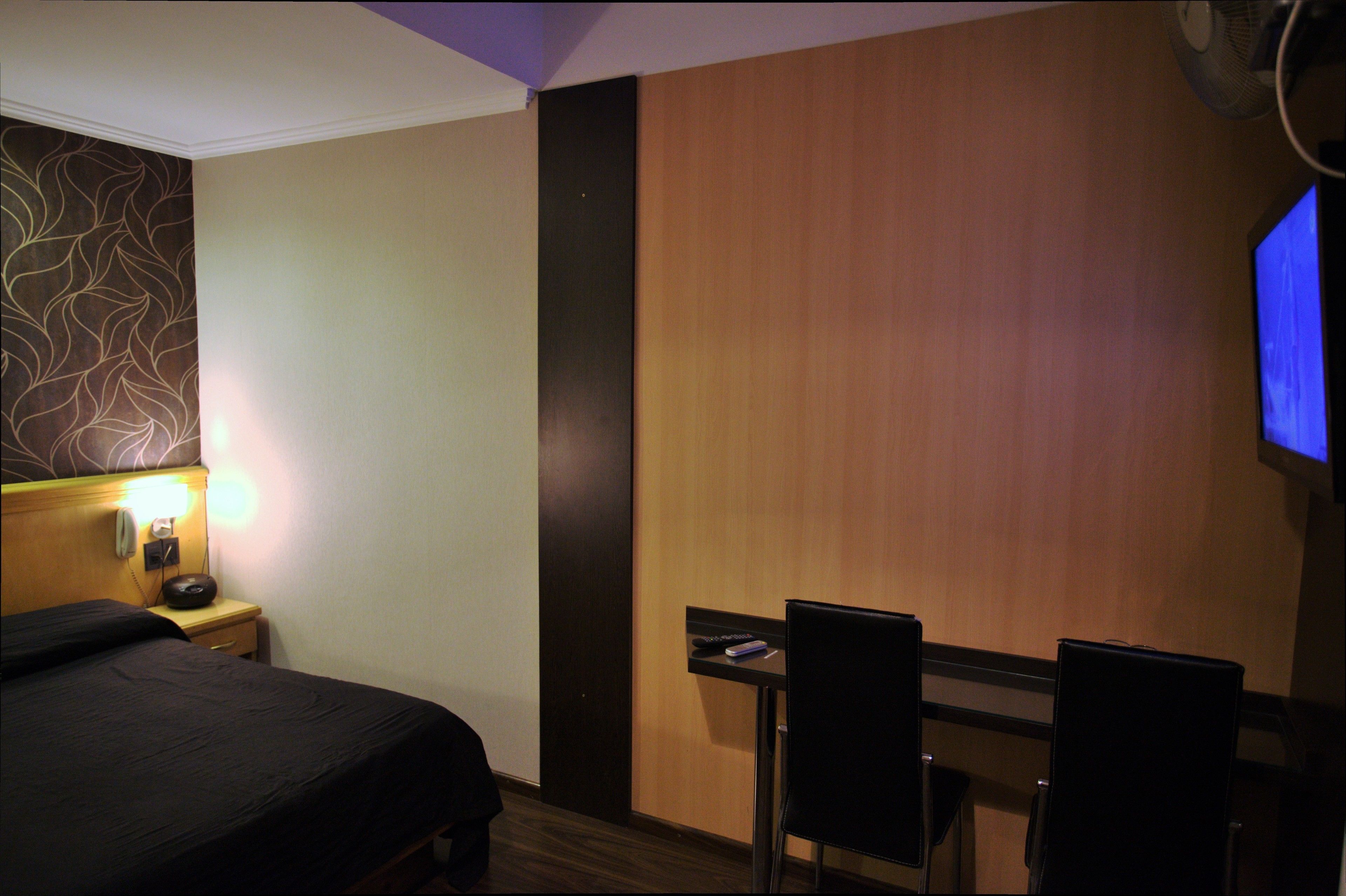 Une chambre d’hôtel équipée d’un lit, d’une table de chevet, d’une lampe et d’un téléviseur fixé au mur.