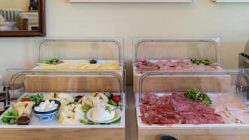 Ein Buffet mit verschiedenen Speisen, darunter Käse, Fleisch und Salate.