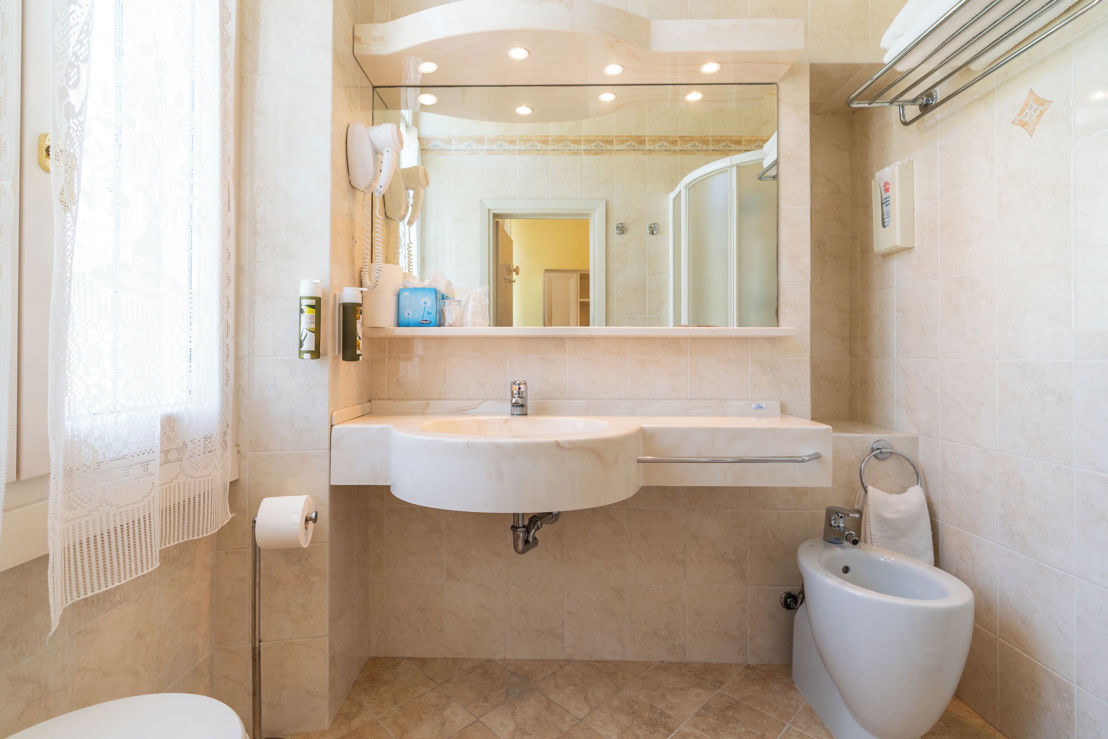 Une salle de bain équipée d’un lavabo, d’un miroir, de toilettes et d’un bidet.