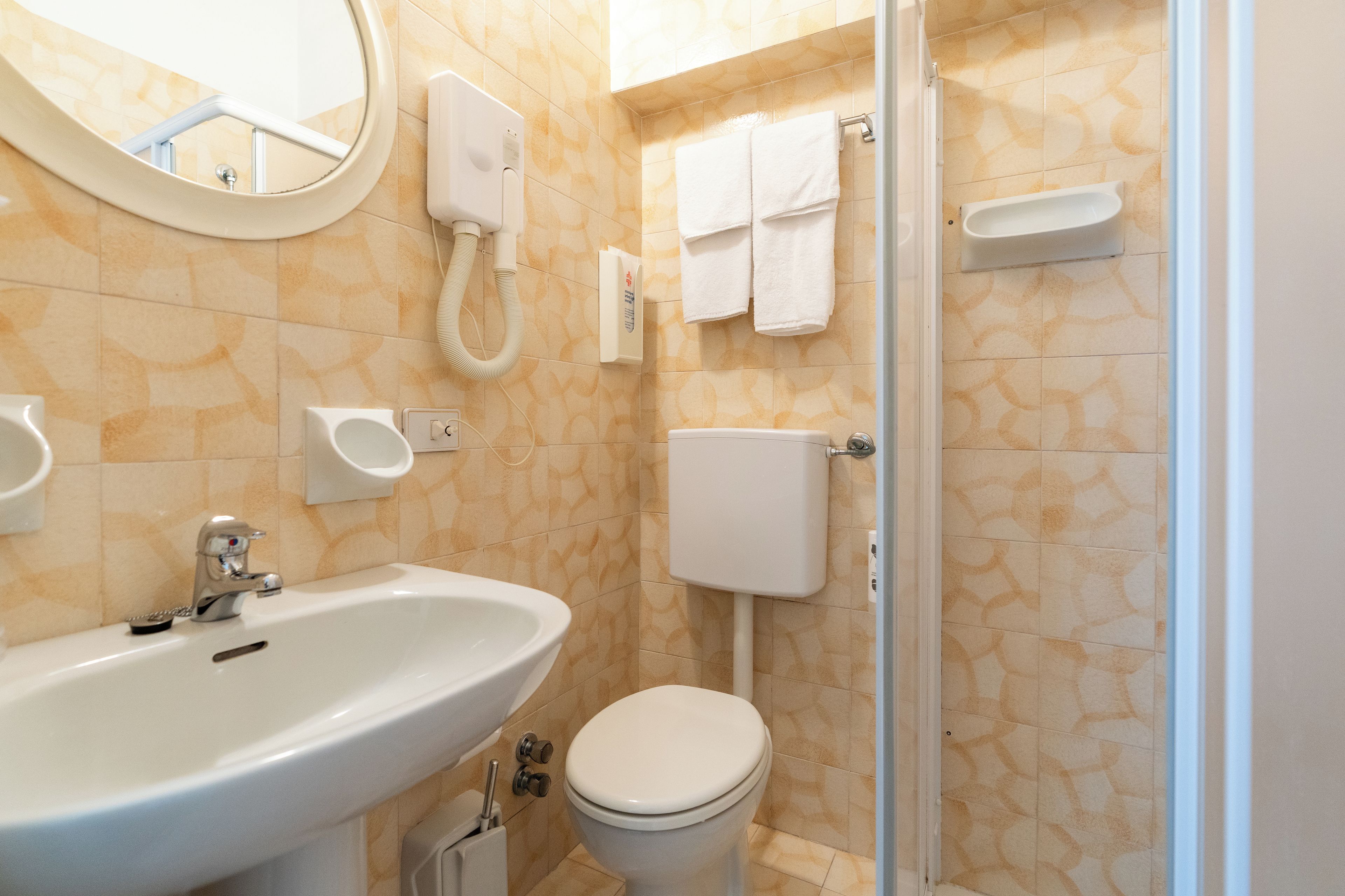 Et badeværelse med vask, toilet og bruseområde.