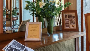 A reception desk with a framed menu, a vase with white flowers, and a photo album.