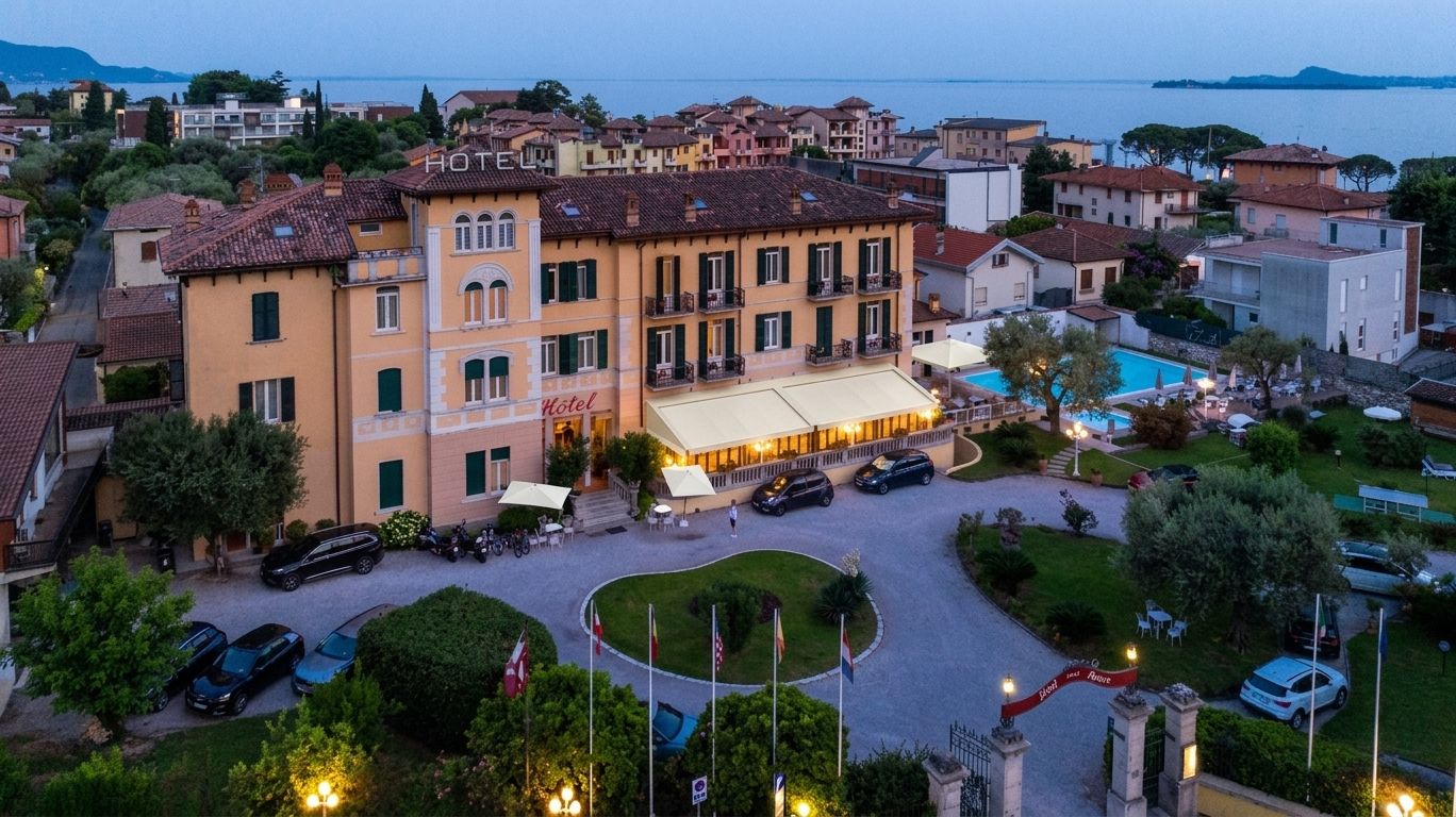 A hotel with a pool, surrounded by a landscaped garden and a view of the sea.