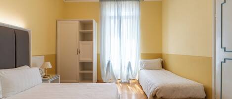 Habitación de hotel con dos camas, un armario, una mesita de noche y una ventana con cortinas.
