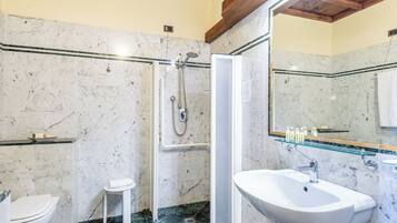 Un baño con ducha, inodoro y lavamanos, todo con paredes de mármol y techo de madera.