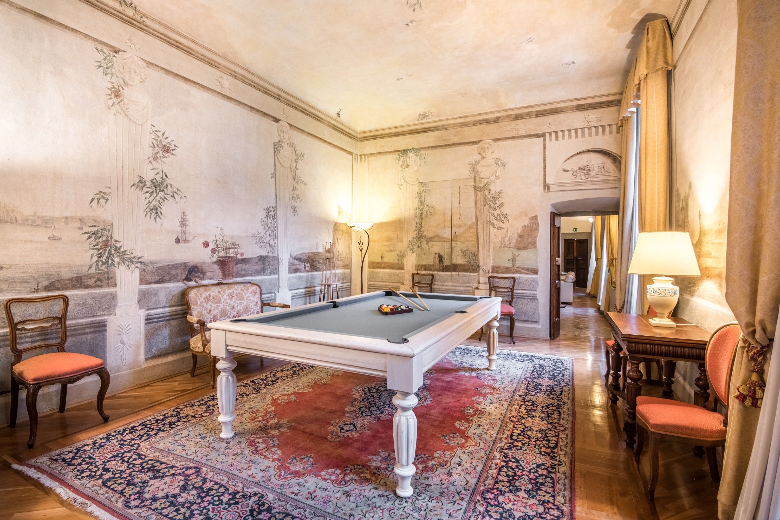 Ein Zimmer mit Pooltisch, Stühlen, Teppich und Lampe.