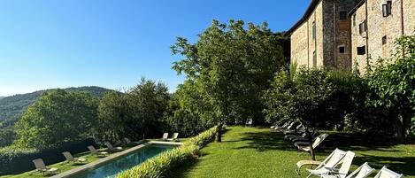 A poolside area with lounge chairs and a stone building in the background.