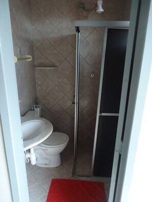 A small bathroom with a toilet, sink, and shower. - Hotel Pousada Sol (Natal)