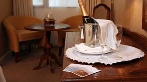 Une chambre d’hôtel avec une table en bois, une bouteille de champagne, un verre et une lampe.