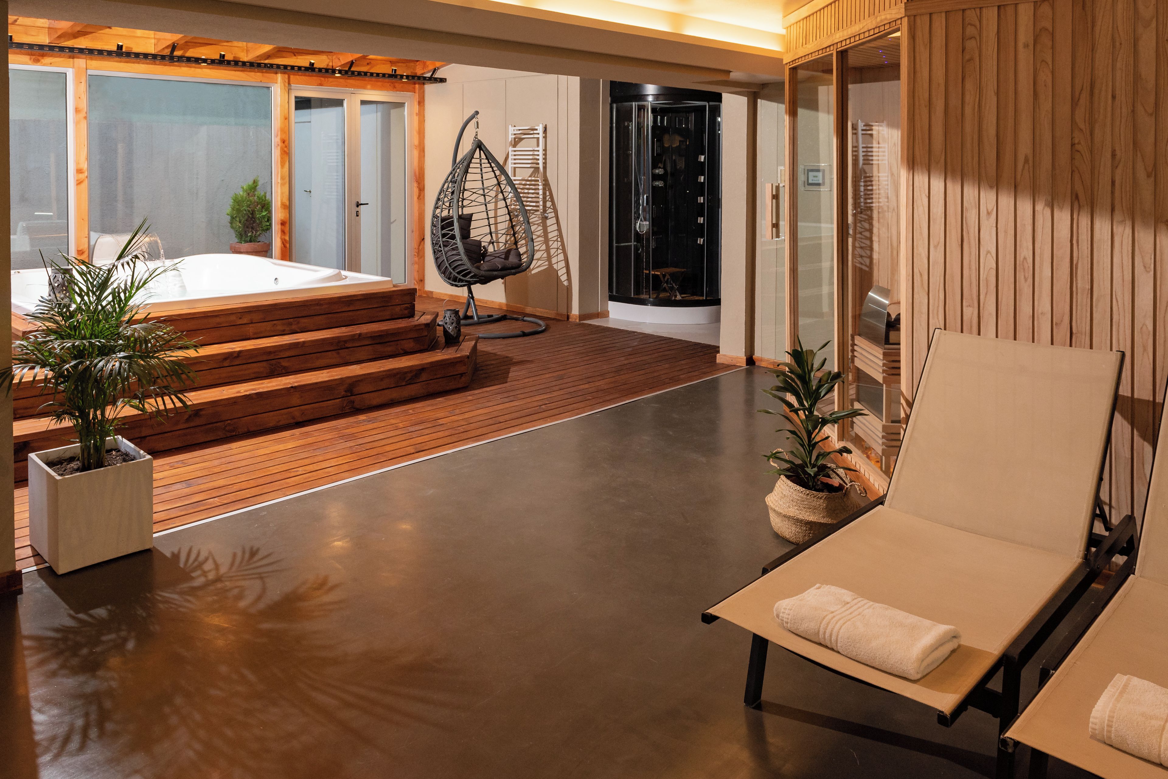 A modern interior with a wooden deck, a hanging chair, a sauna, and a lounge area.