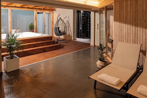 A modern interior with a wooden deck, a hanging chair, a sauna, and a lounge area.
