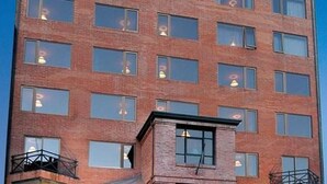A multi-story brick building with numerous windows and a small attached structure with a balcony. - Crans Montana Hotel (San Carlos de Bariloche)