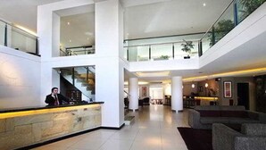 A spacious lobby with a reception desk, seating area, and a staircase leading to an upper level. - Crans Montana Hotel (San Carlos de Bariloche)