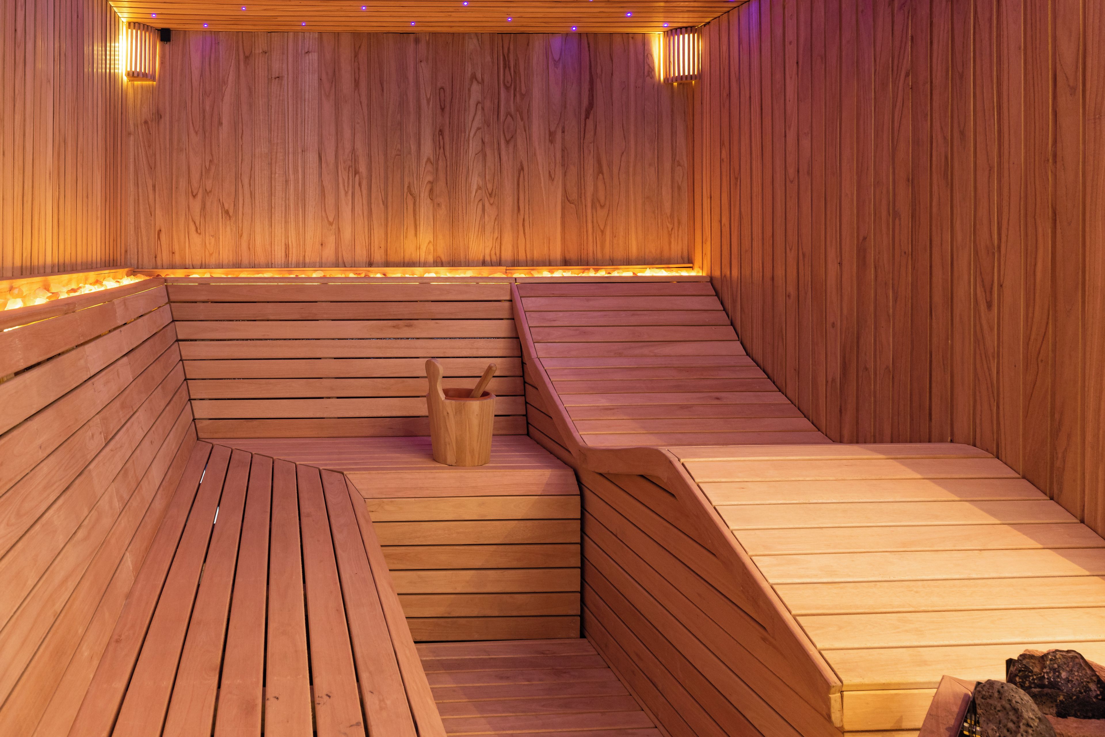 Una sauna con panche in legno e una fonte di calore centrale.