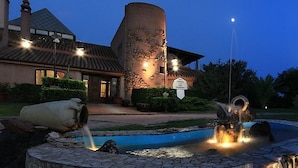 A fountain with water features in front of a building with a stone facade and a sign. - I Ginepri (Quartucciu)