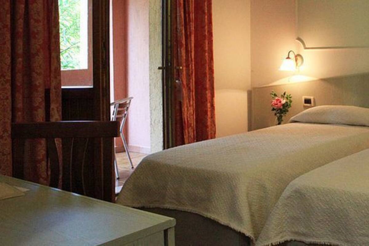 Una habitación de hotel con dos camas, un escritorio y una mesita de noche con una lámpara.