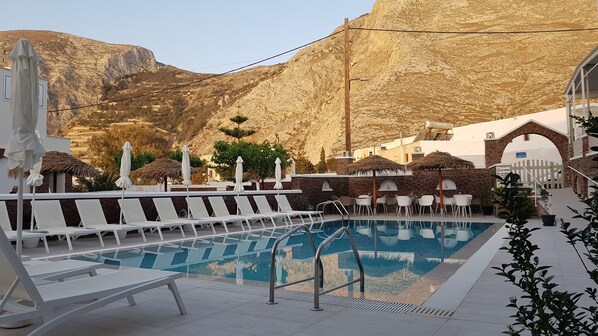 Una piscina al aire libre de temporada, sombrillas