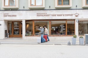 Un edificio con un letrero que indica 'Hotel Cap Polonio' y 'Marcopolo Restaurant Take Away & Coffee'.