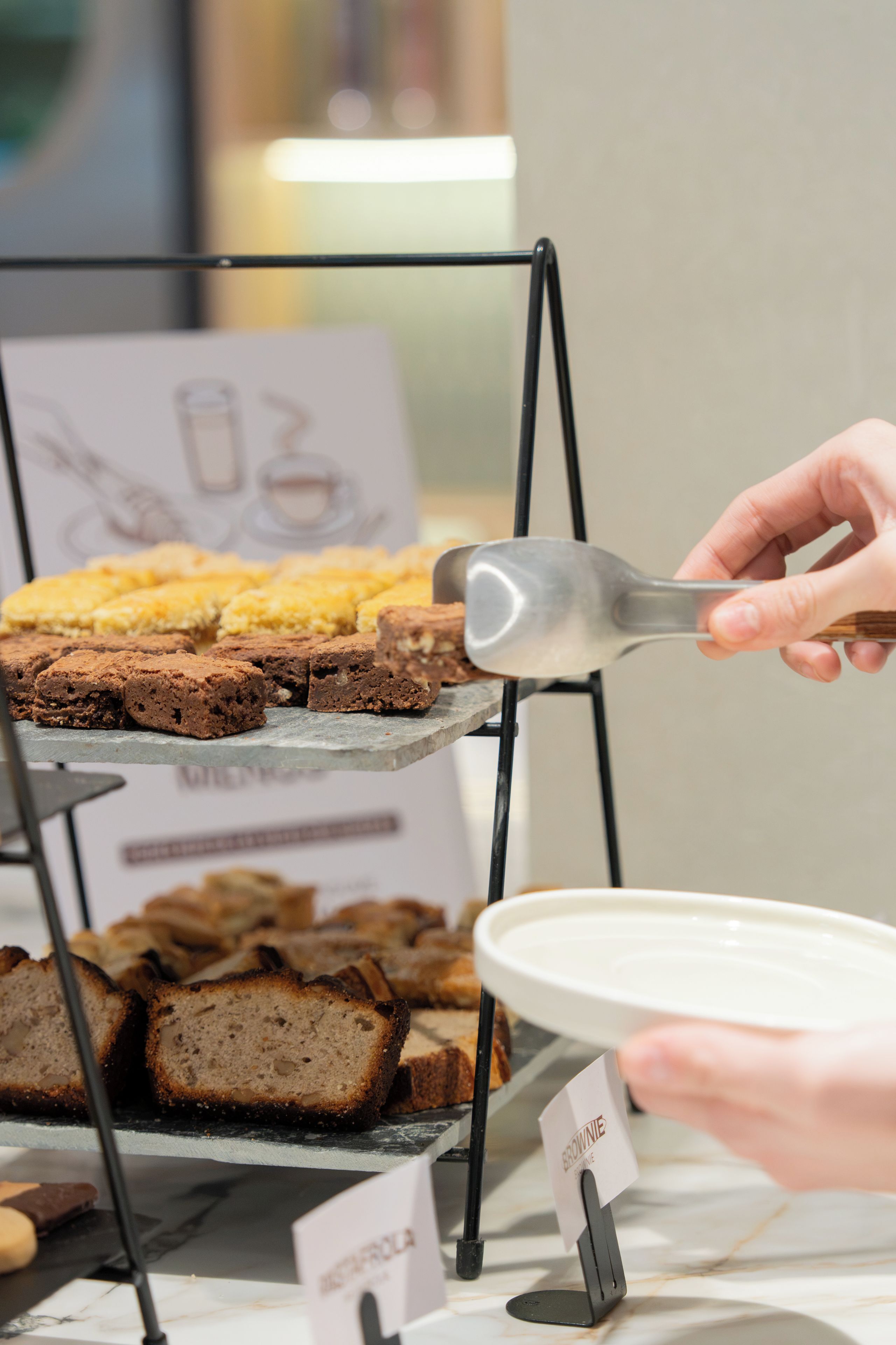 Une vitrine remplie de pâtisseries, avec une pancarte indiquant la présence de brownies.