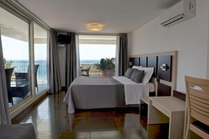Una habitación de hotel con cama, escritorio y vista al océano.