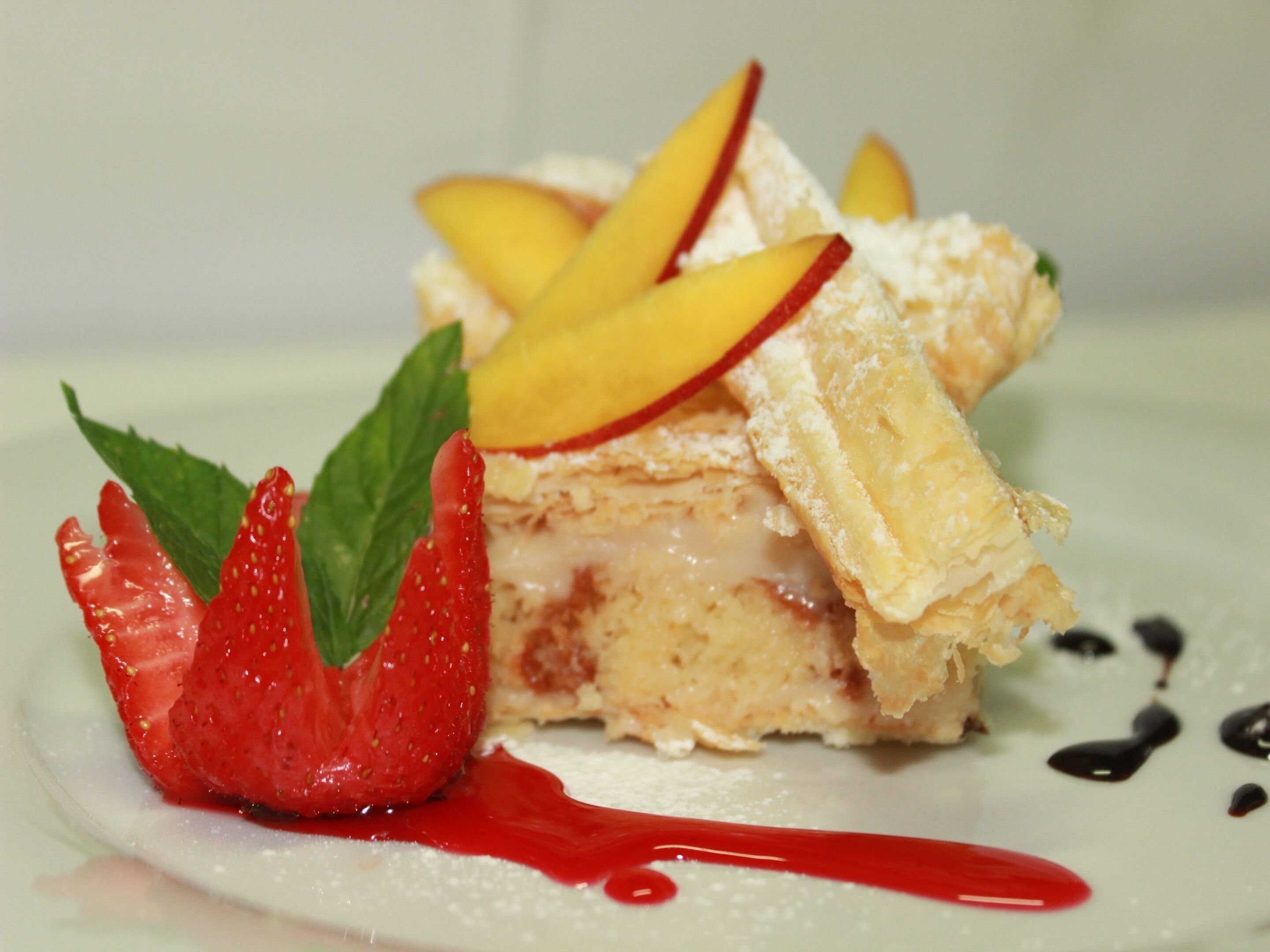 Un postre con fruta y una decoración de fresa sobre un plato blanco.