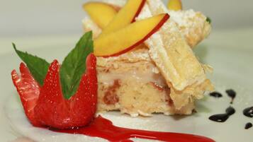 Un dessert aux fruits, décoré de fraises, présenté sur une assiette blanche.