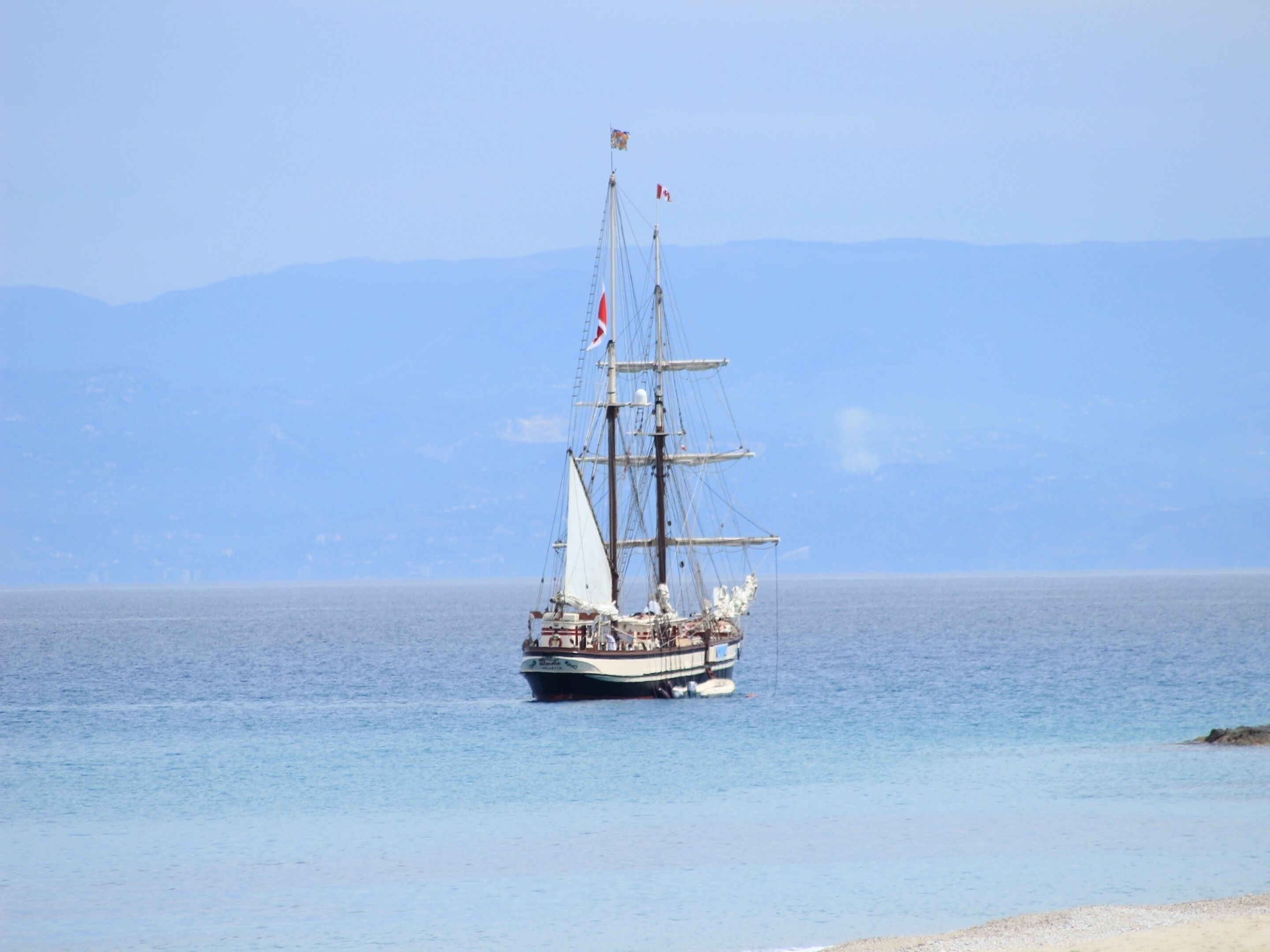 A tall ship with multiple masts sailing on calm waters.