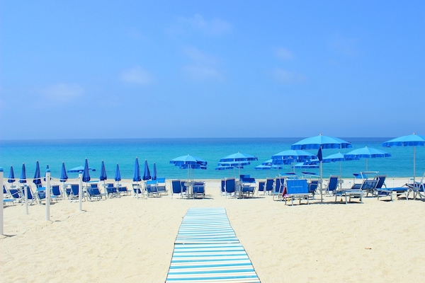 Praia particular, espreguiçadeiras, guarda-sóis, toalhas de praia